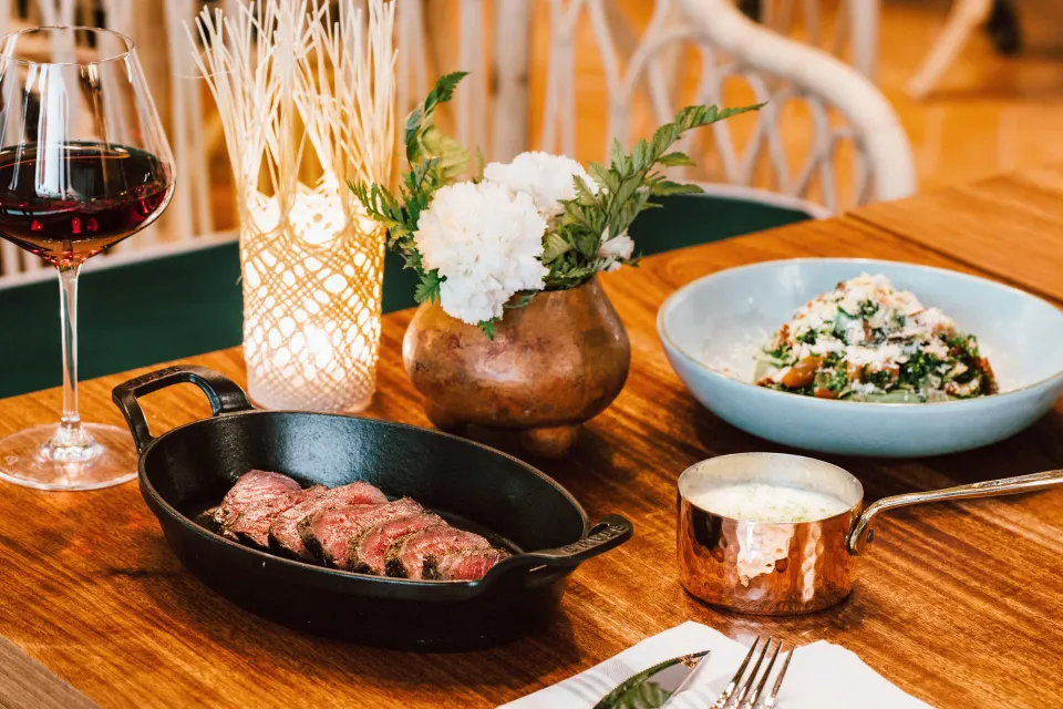 Sliced steak in a cast-iron pan with sides and wine at Hotel Esencia