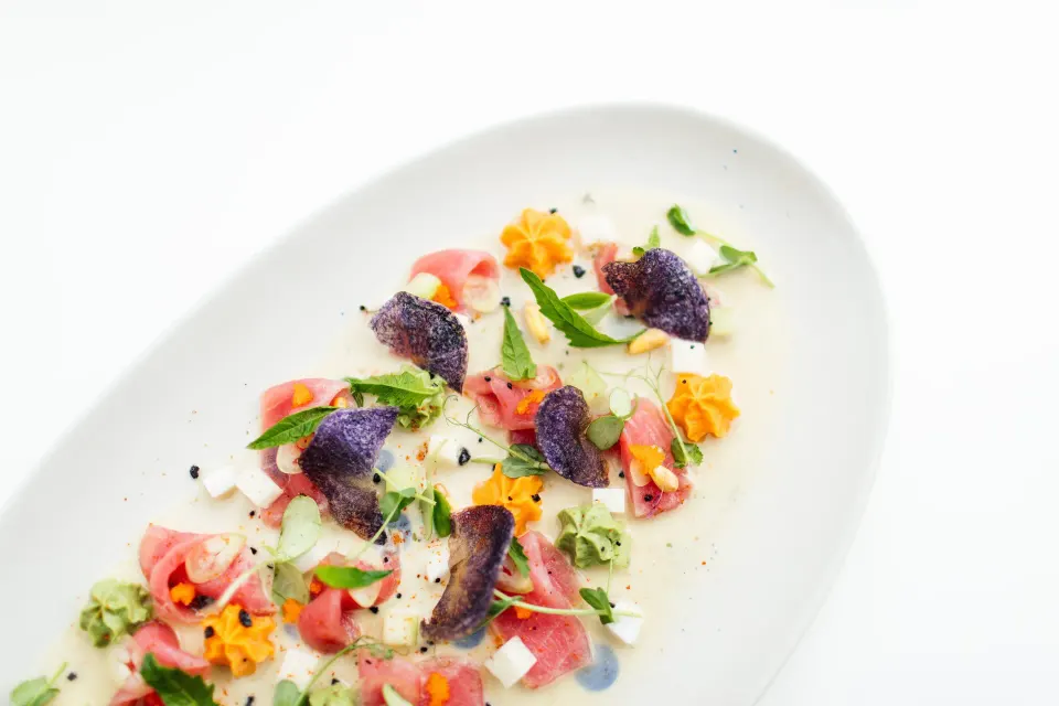 Delicate plated appetizer with edible flowers on white at Hotel Esencia