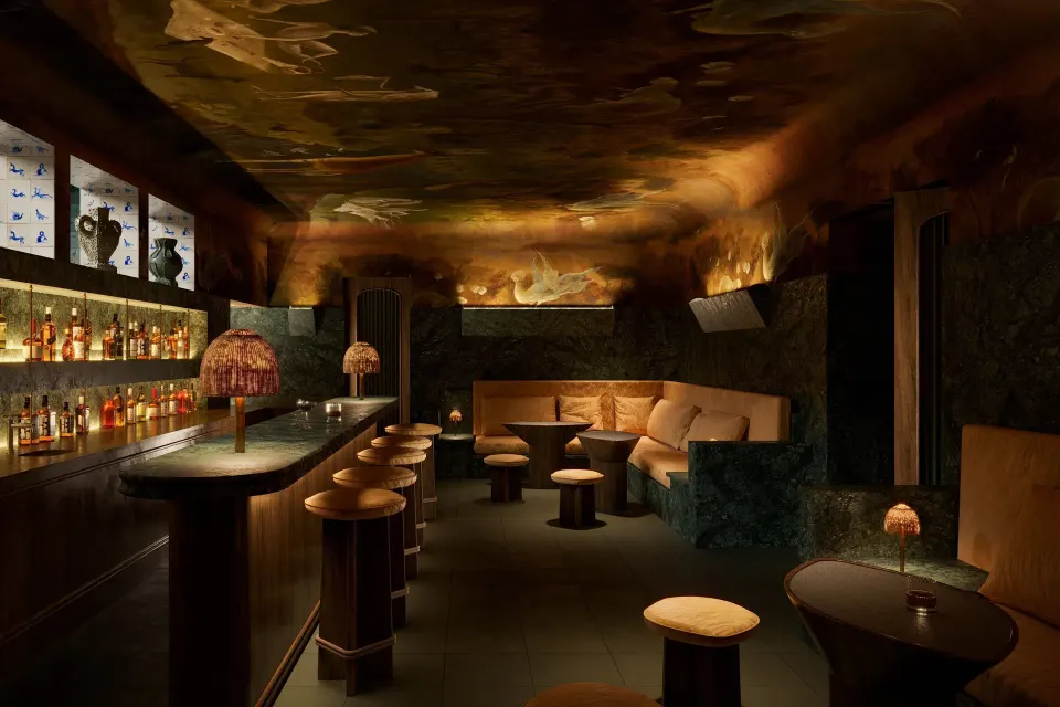 Dimly lit cocktail bar interior with stools and low seating at Hotel Esencia