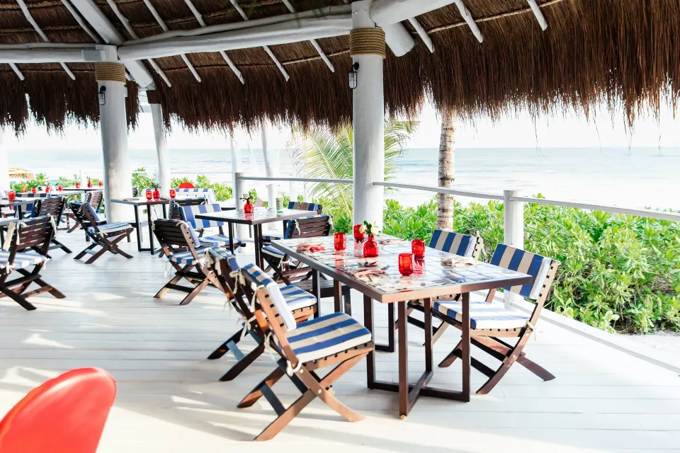 Open-air palapa dining terrace with striped cushions and ocean view at Hotel Esencia