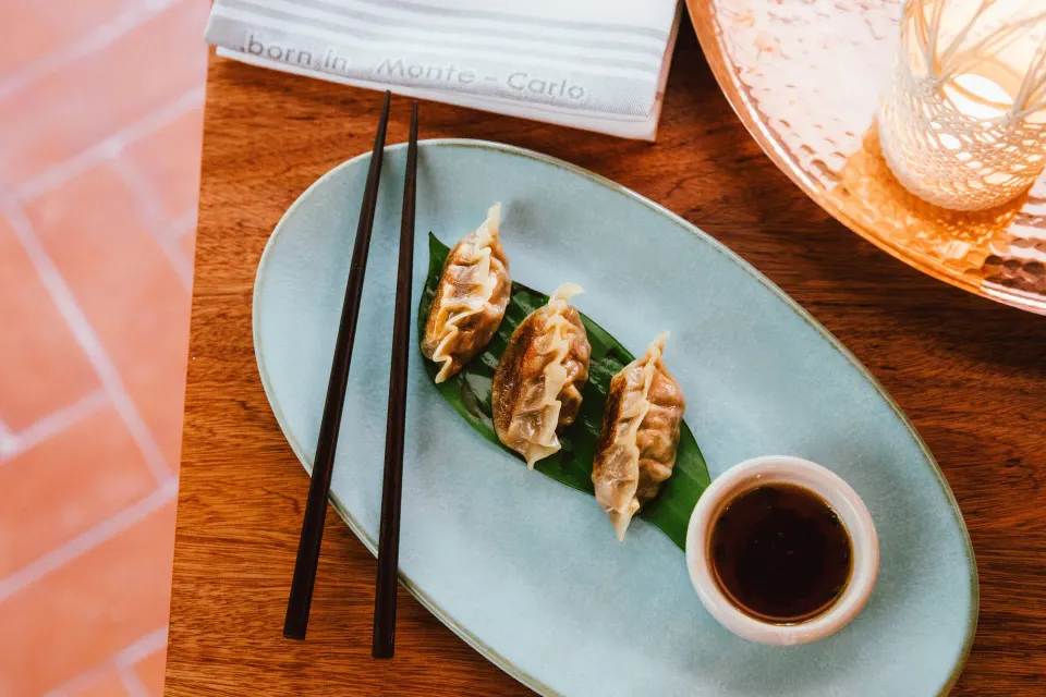 Steamed dumplings with dipping sauce on a green plate at Hotel Esencia.