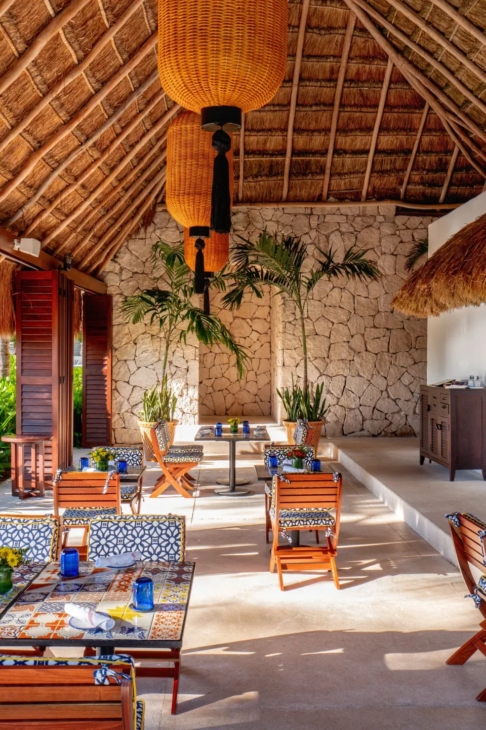 Thatched dining room with tiled tables and hanging lights at Hotel Esencia