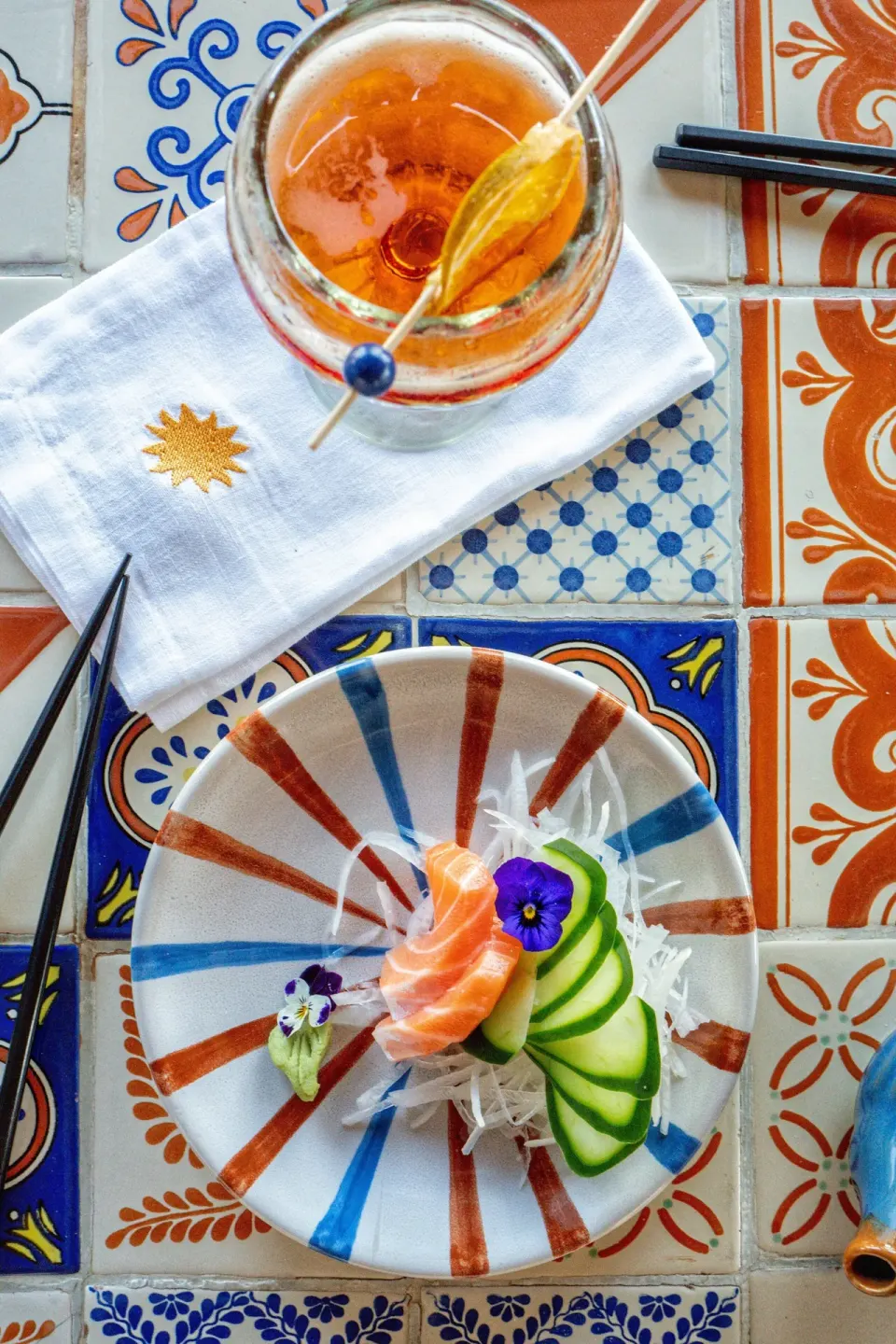 Small sashimi plate and cocktail on decorative tiles at Hotel Esencia