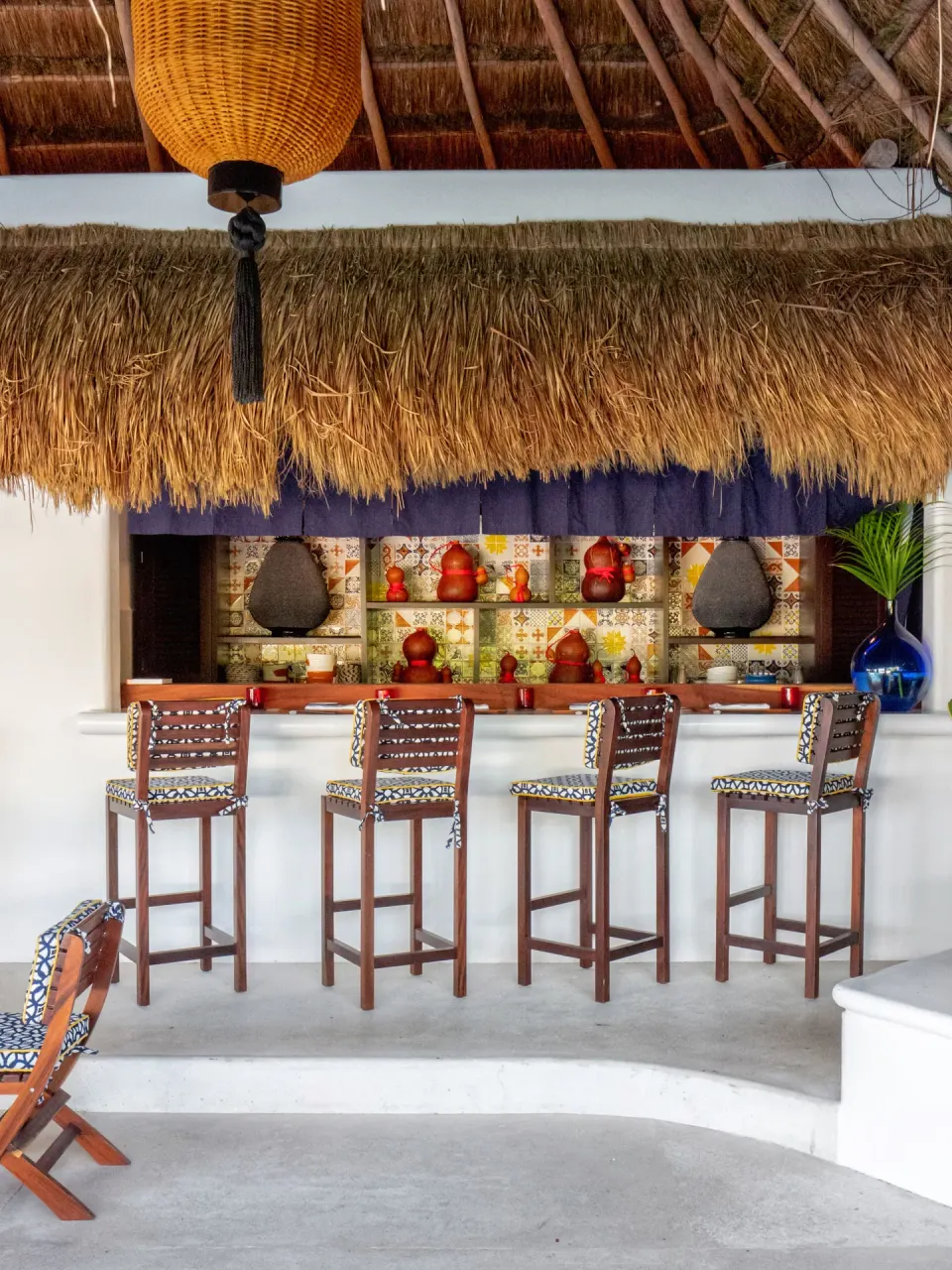 Thatched bar with stools and decorative shelves at Hotel Esencia