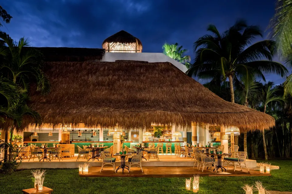 Thatched-roof palapa restaurant lit at night at Hotel Esencia