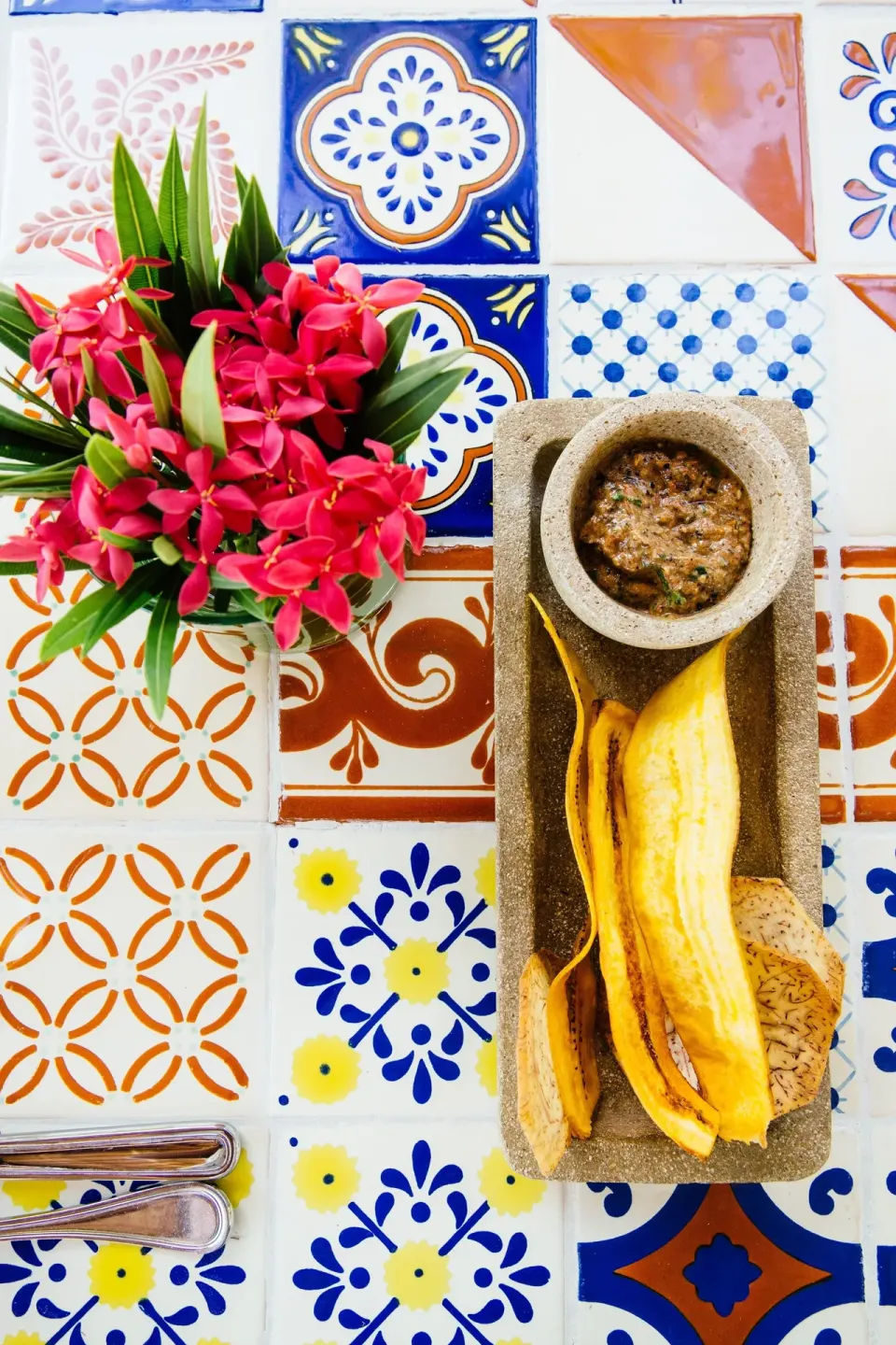 Tiled tabletop with tropical flowers and a banana snack at Hotel Esencia