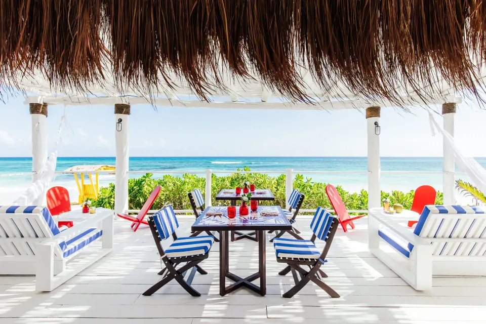 White painted palapa seating area with striped cushions and sea view at Hotel Esencia