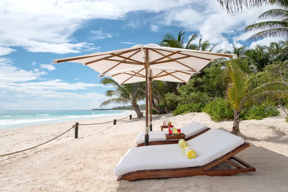Two sun loungers and umbrella on the sandy beach at Hotel Esencia