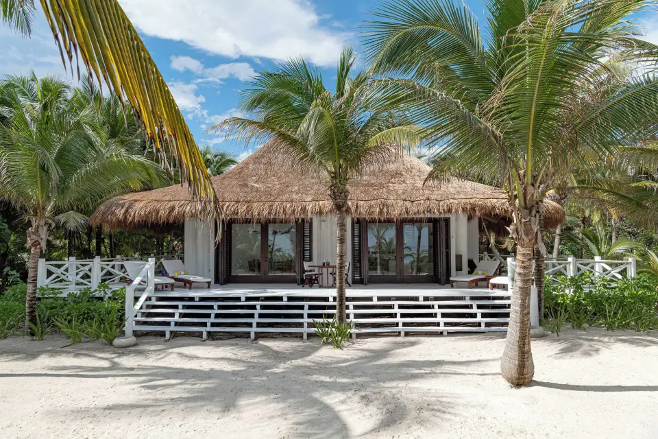 Raised beachfront terrace of the Presidential Bungalow with palms and outdoor seating at Hotel Esencia.