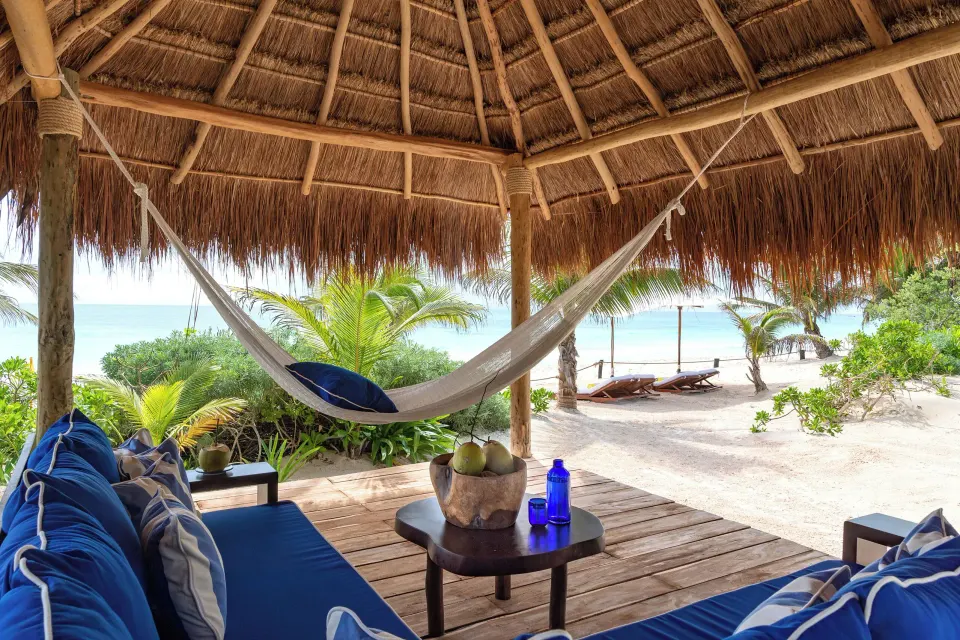 View from inside a palapa showing hammock, seating and a glimpse of the ocean at Hotel Esencia.