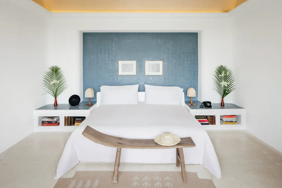 Neutral bedroom with king bed, built-in shelves and blue accent wall at Hotel Esencia