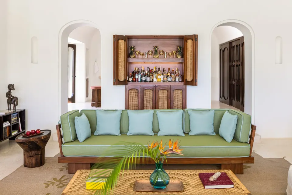 Green upholstered sofa and tucked-away minibar cabinet in The Hotel Esencia at Hotel Esencia