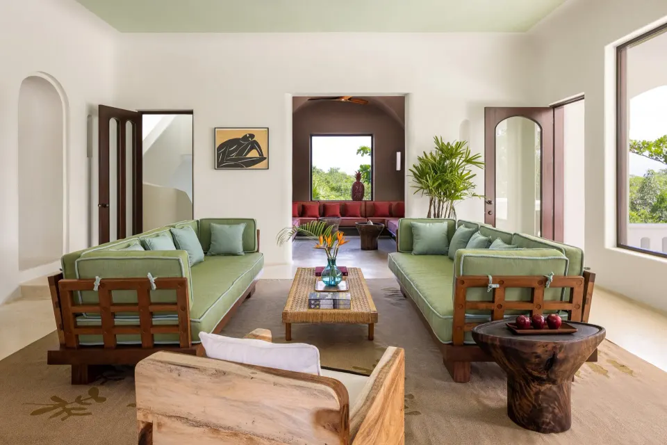 Bright living room with paired green sofas and open archways in The Hotel Esencia at Hotel Esencia