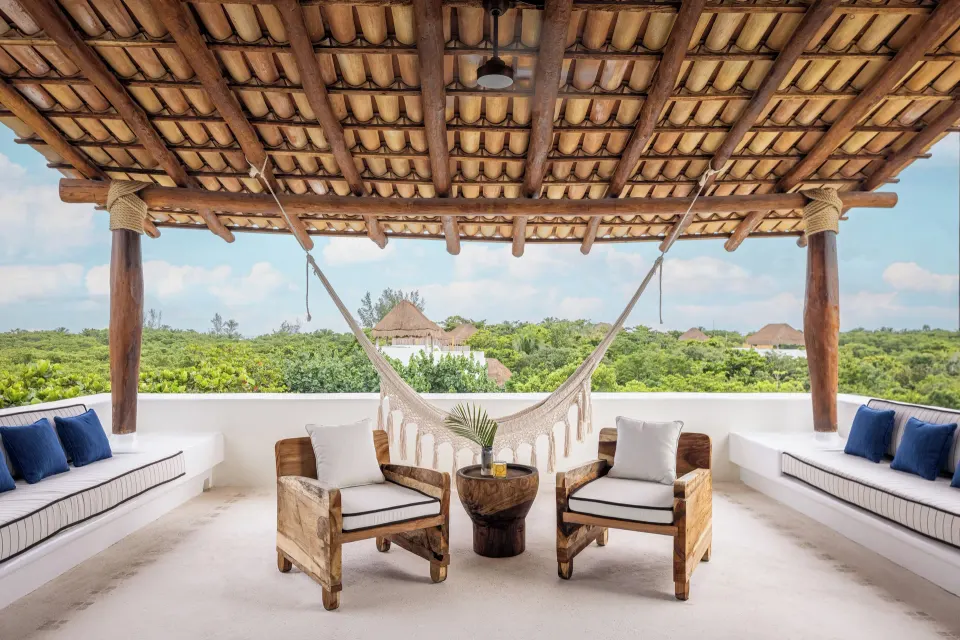 Living area with sofas and green chairs leading to an arched bedroom doorway at Hotel Esencia