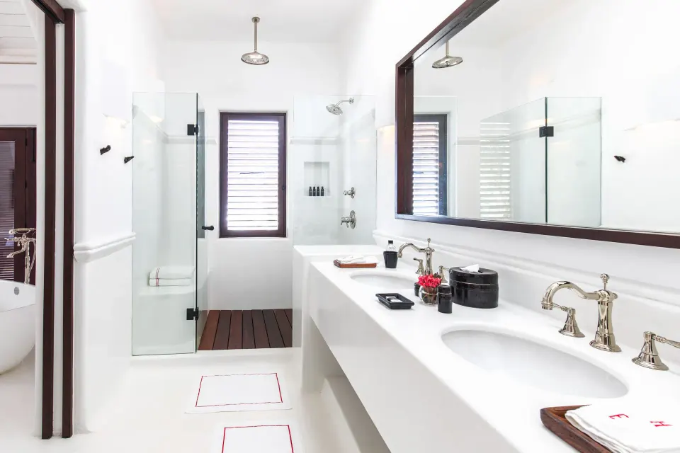Bright bathroom with double sink, glass shower and large mirror at Hotel Esencia.