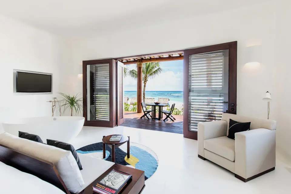 White living area and balcony opening to the beach view at Hotel Esencia.