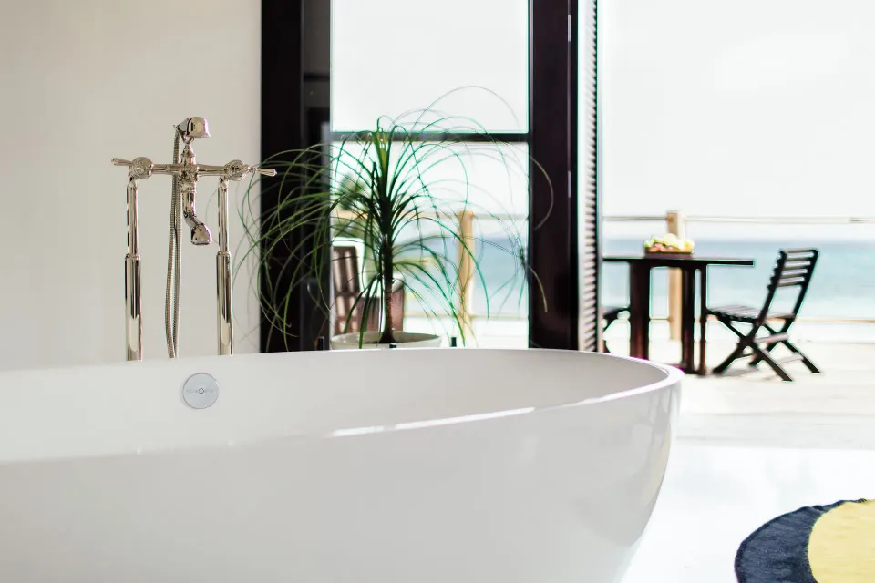 Freestanding bathtub framed by the balcony view toward the ocean at Hotel Esencia.