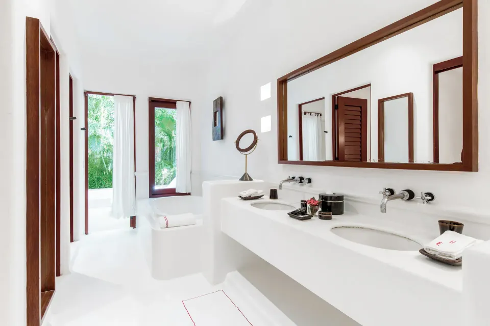 Spacious white bathroom with double sink and large mirror in the Jungle Suite at Hotel Esencia
