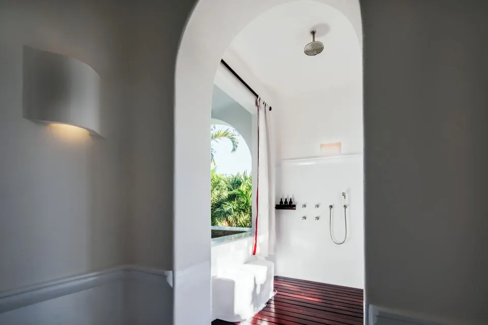 Open shower with overhead rain shower and arched doorway to greenery in the Jungle Suite at Hotel Esencia