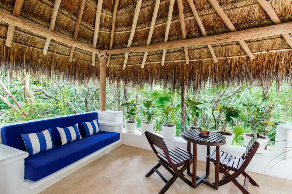 Thatched-roof private terrace with blue cushion bench and dining table at Hotel Esencia