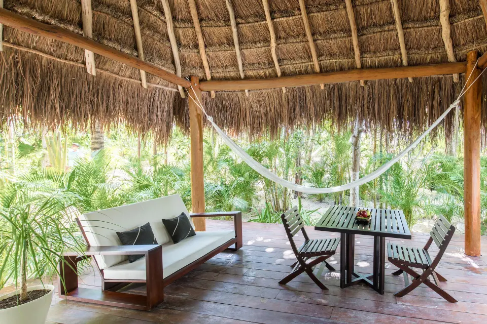Shaded Jungle Suite veranda with hammock, sofa and dining table at Hotel Esencia