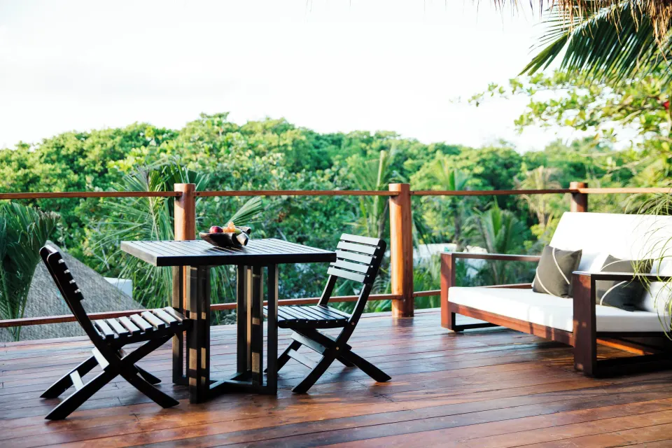 Deck dining table and sofa overlooking palms from Jungle Suite at Hotel Esencia