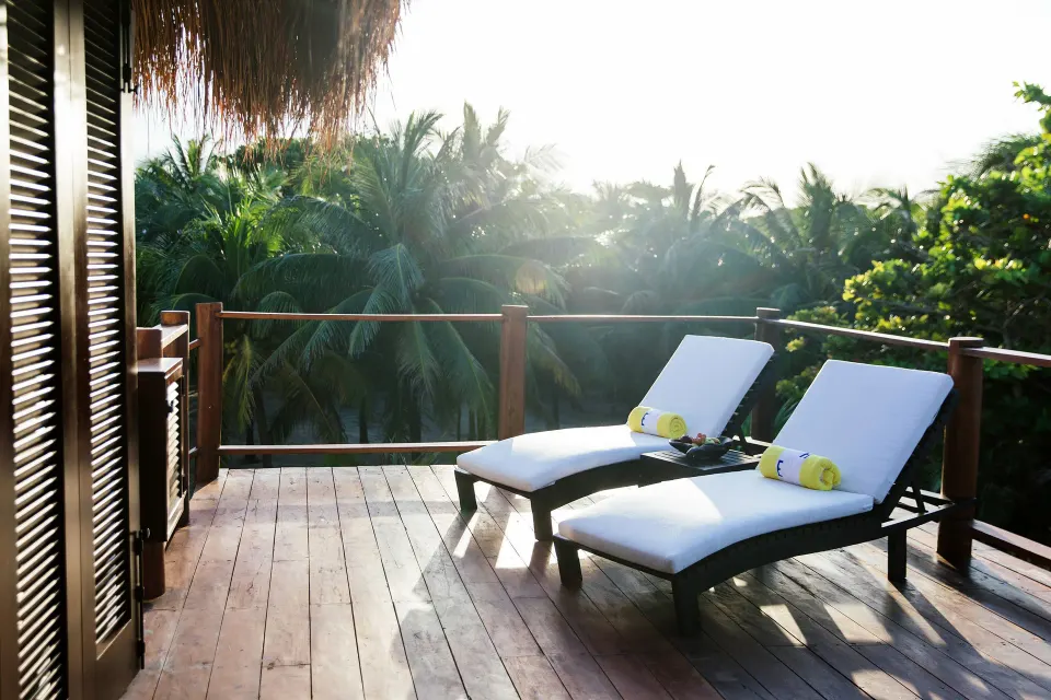 Wooden deck with two lounger chairs overlooking trees at Hotel Esencia