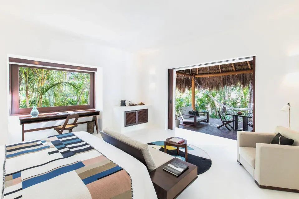 Jungle Suite king bed with open doors to covered terrace at Hotel Esencia