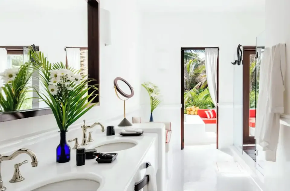 Bright bathroom vanity with double sinks and doorway to terrace in the Suite (Master Beach) at Hotel Esencia