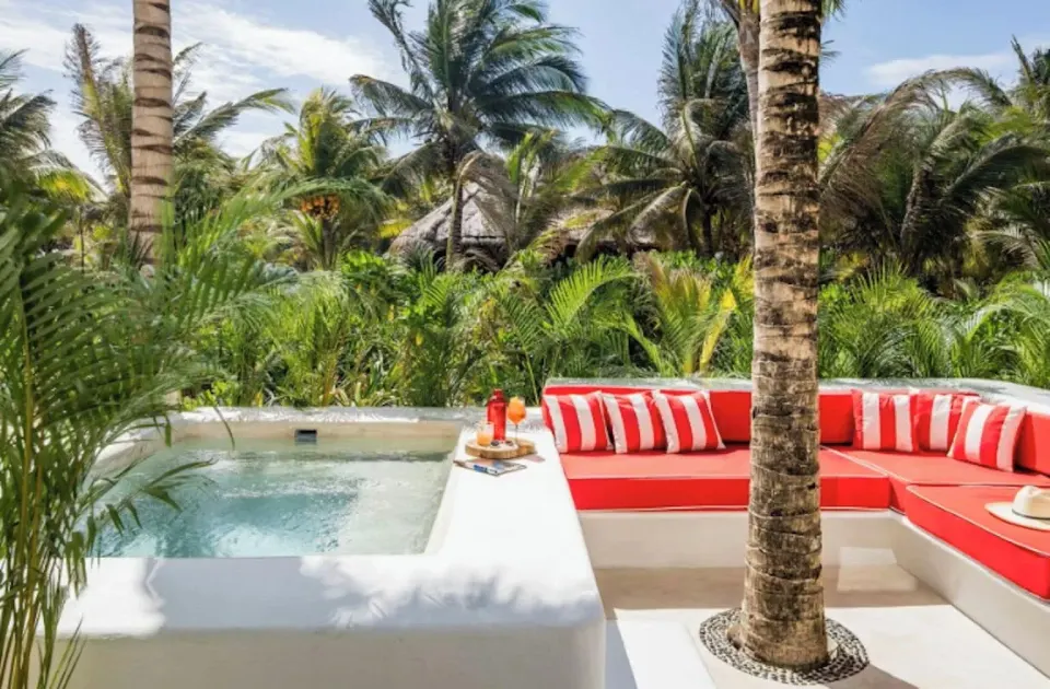 Corner plunge pool and red striped cushions amid tropical palms at Hotel Esencia (Master Beach)