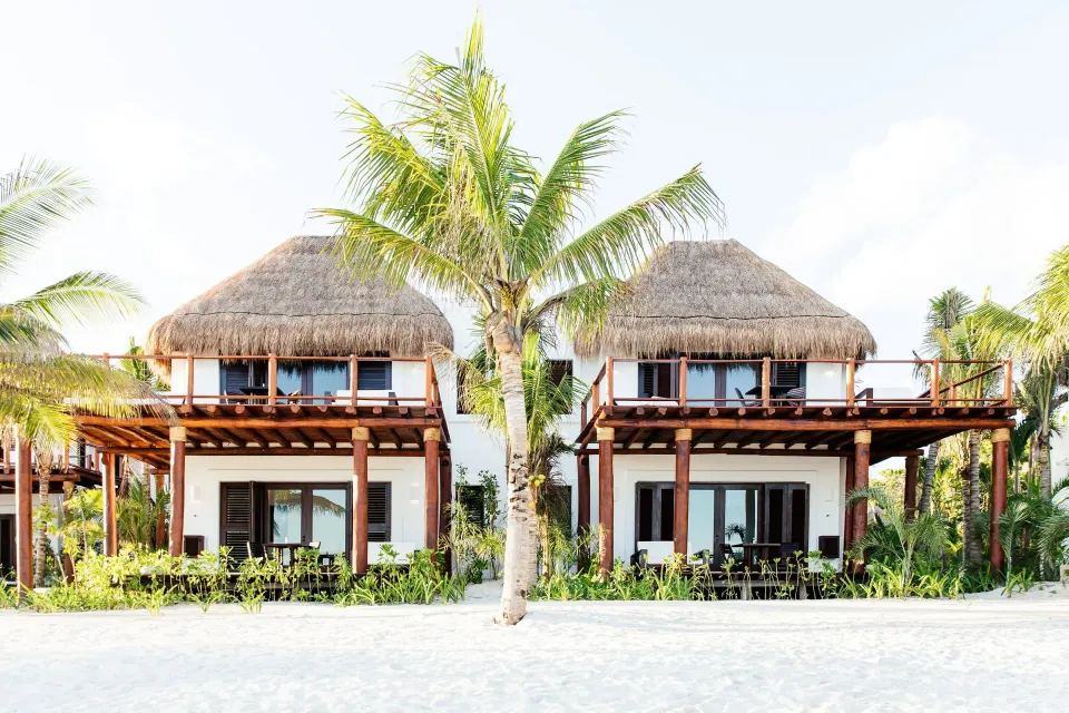 Exterior view of beachfront thatched-roof suites on the sand at Hotel Esencia