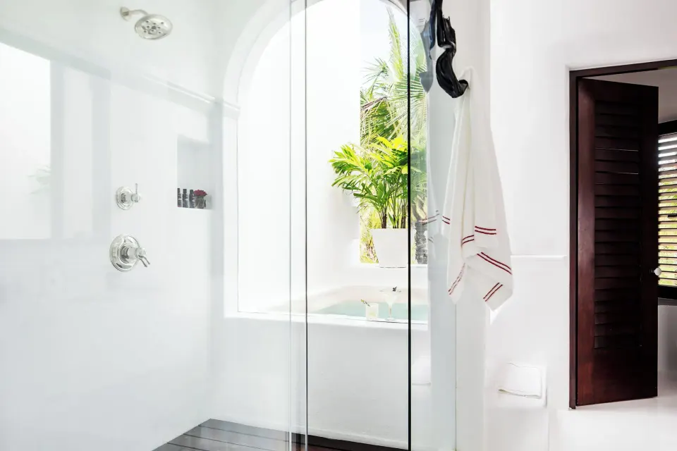 Glass-enclosed shower with arched window and view into the terrace area at Hotel Esencia (Master Beach)