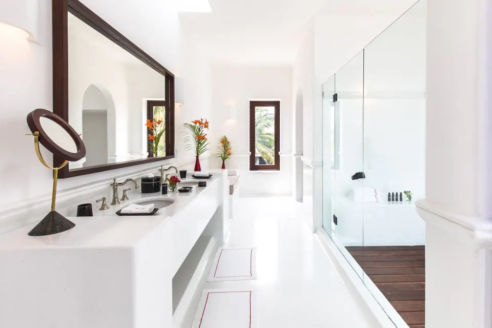 Long white bathroom with glass shower and twin sinks in the Suite (Master Beach) at Hotel Esencia