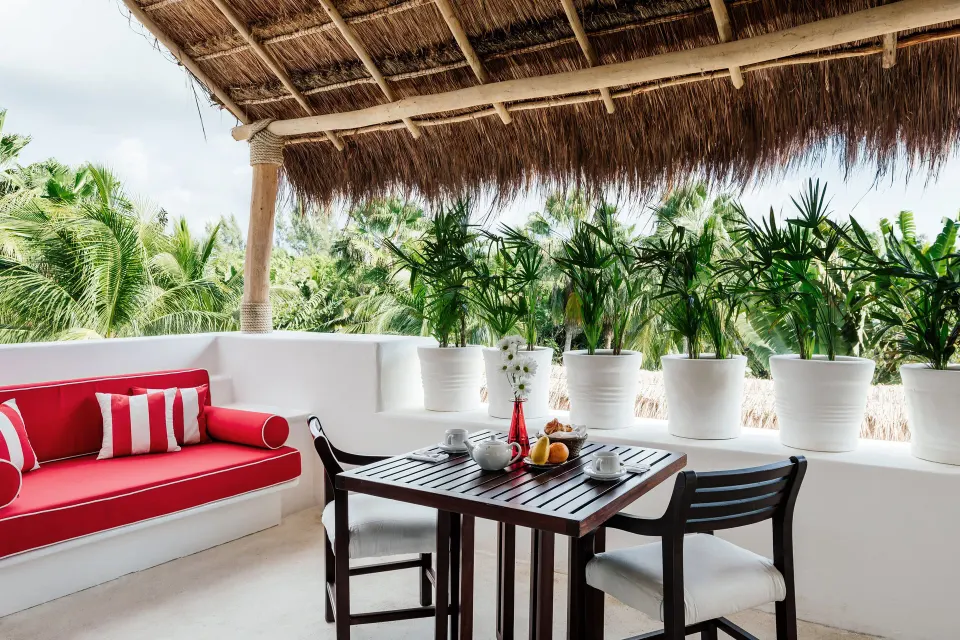 Shaded balcony seating with red cushions and tropical view at Hotel Esencia