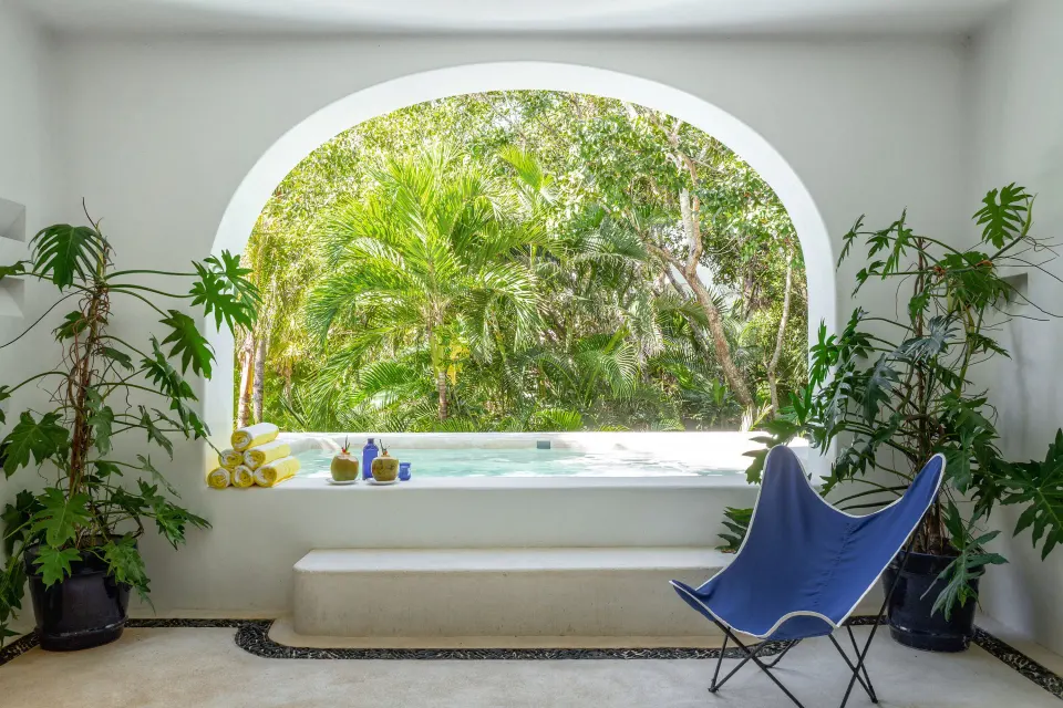 Built-in plunge pool framed by an arched window and jungle at Hotel Esencia