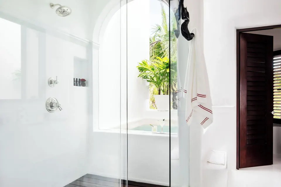 Glass-enclosed shower and arched window with tub in the Master Suite at Hotel Esencia
