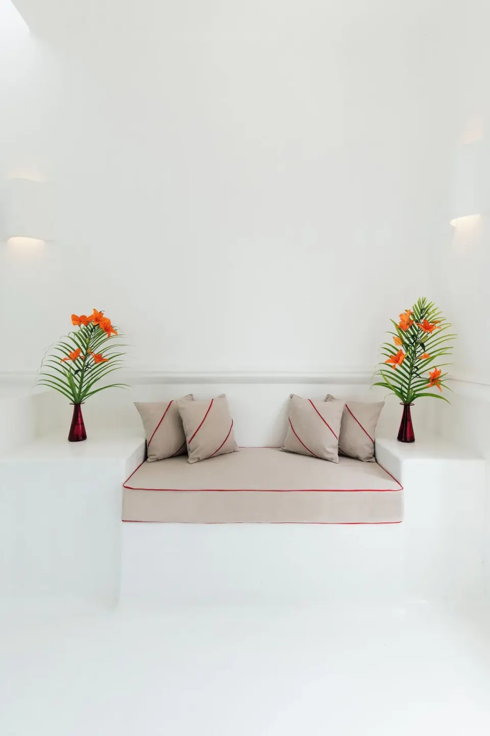 Built-in white bench with cushions and floral vases in master suite at Hotel Esencia