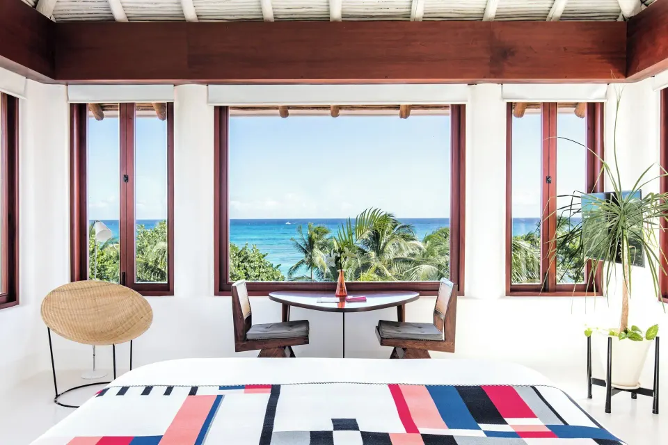 King bed facing large windows with direct ocean view at Hotel Esencia