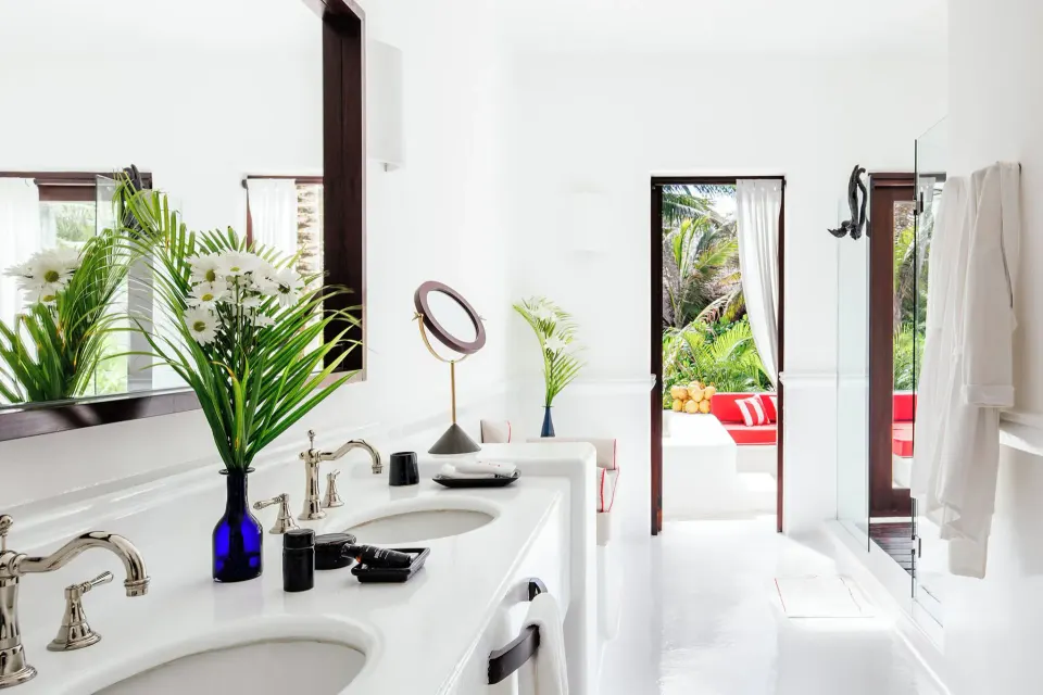 Bright white suite bathroom double vanity with view to outdoor seating at Hotel Esencia