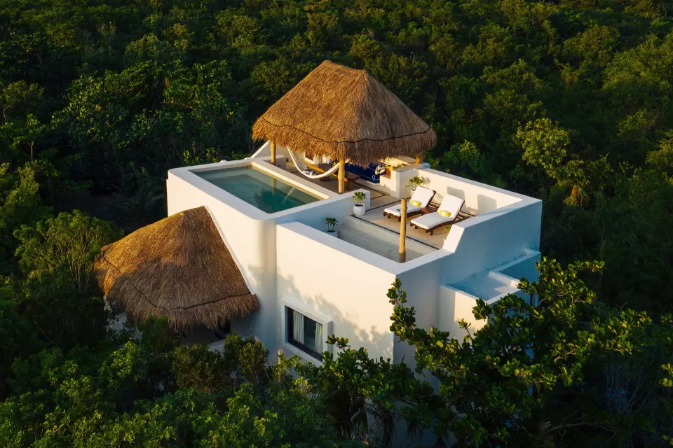 Aerial view of white villa with rooftop palapa, pool and loungers at Hotel Esencia