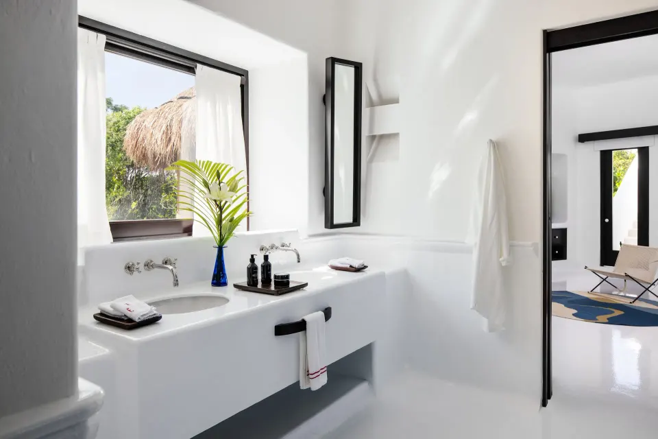 Bright white bathroom with double basins and window in the Rooftop Wellness Suite at Hotel Esencia