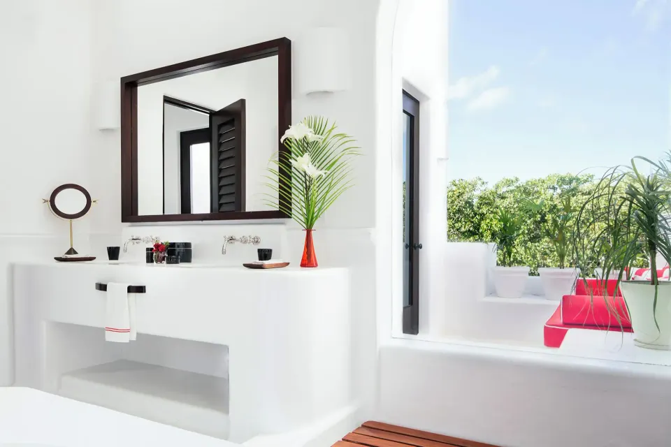 Bathroom vanity and open terrace with red cushions in the Suite (Rooftop Wellness) at Hotel Esencia.