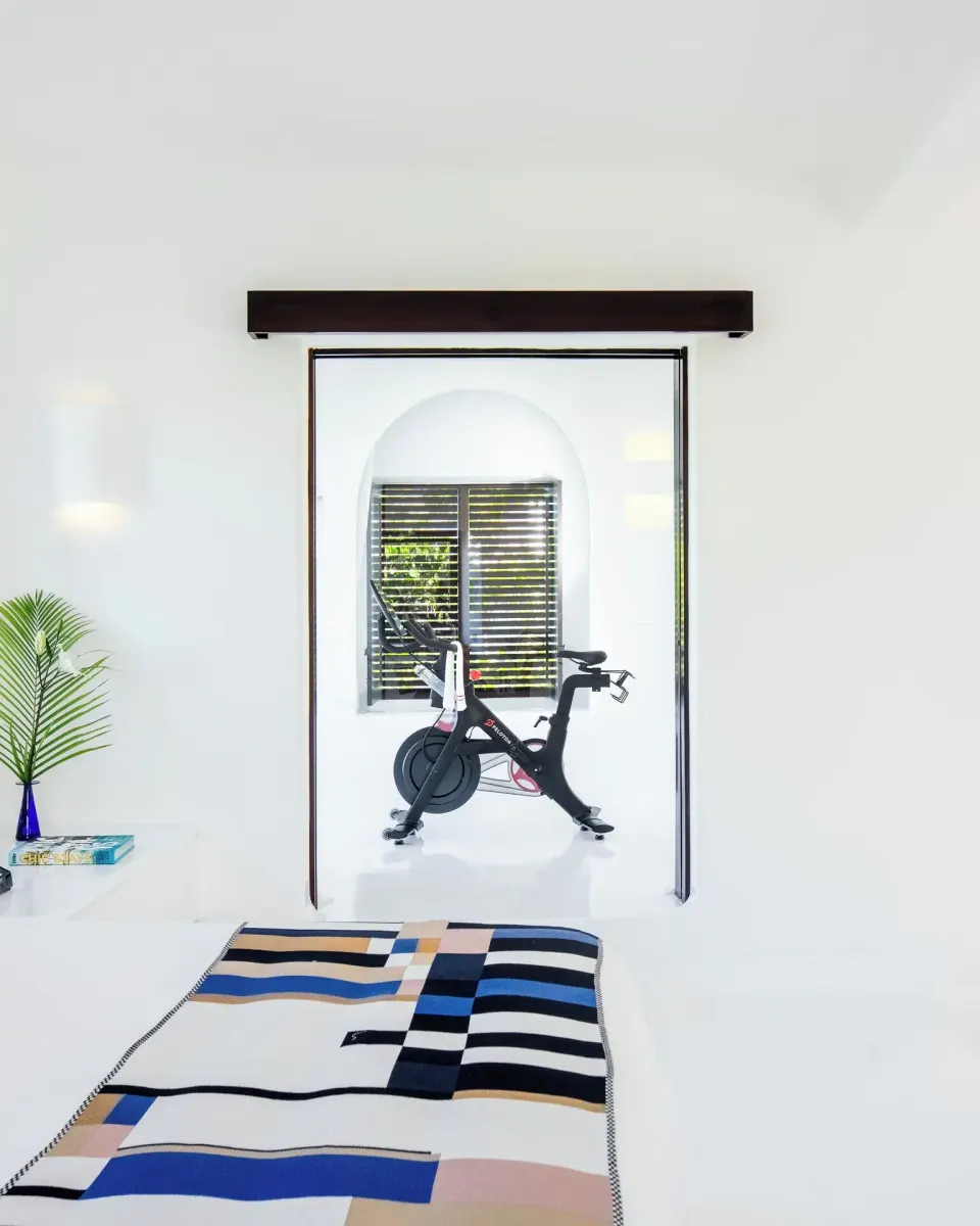 Bedroom view into a doorway with an exercise bike in the Rooftop Wellness Suite at Hotel Esencia