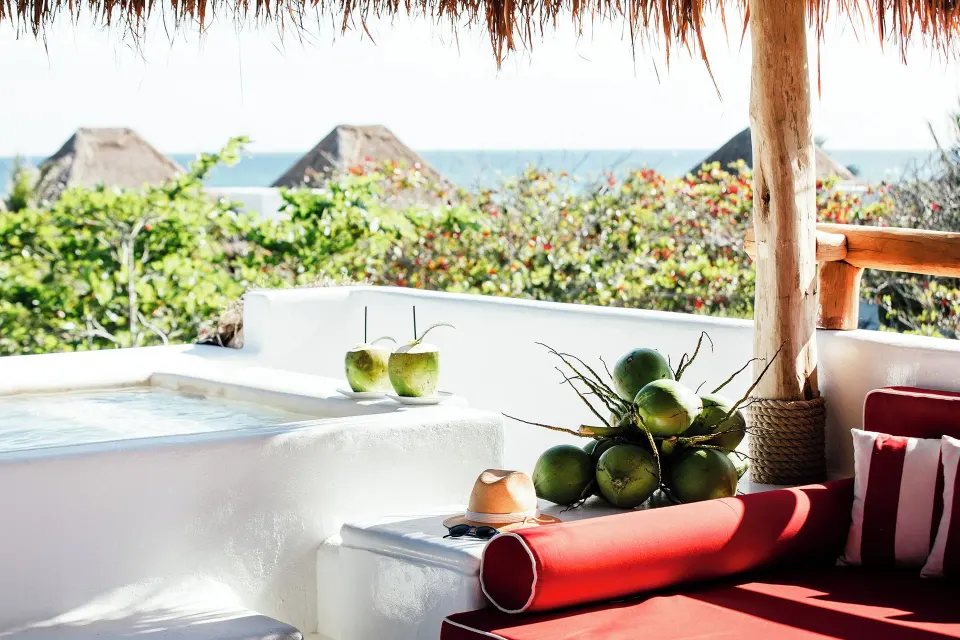 Daybed and fresh coconuts beside a rooftop tub at Hotel Esencia