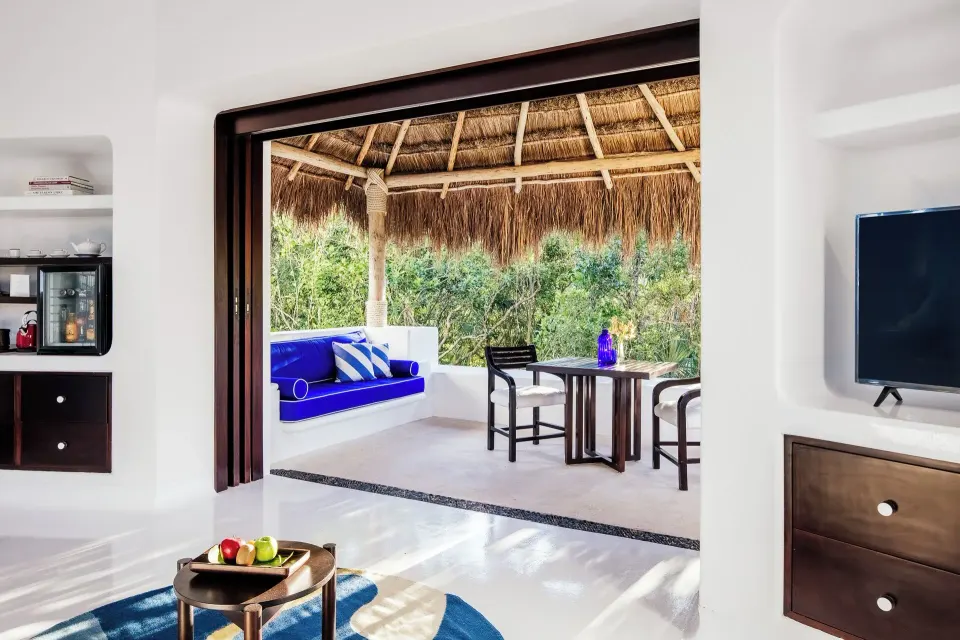 Suite view toward open palapa terrace with built-in blue seating at Hotel Esencia