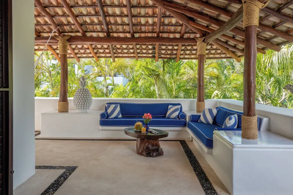 Shaded rooftop lounge with blue cushions and tropical plants at Hotel Esencia