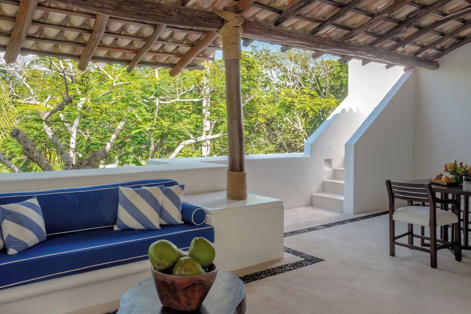 Rooftop terrace seating with blue cushions and view of trees at Hotel Esencia