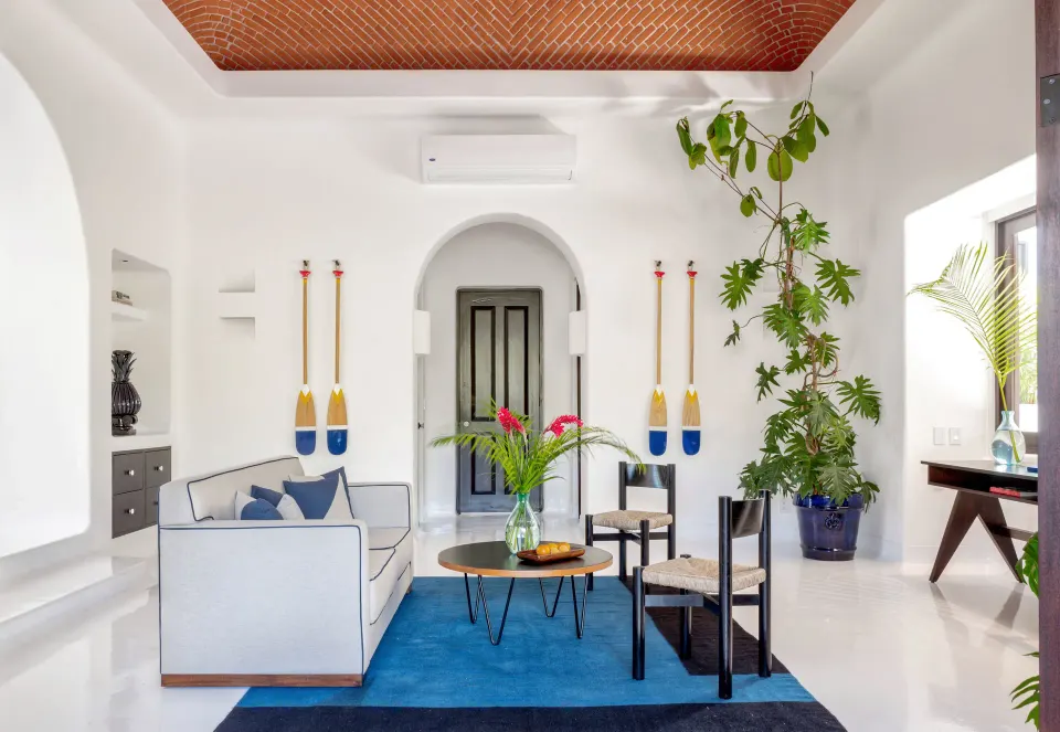 Bright suite living room with blue rug and arched doorway at Hotel Esencia