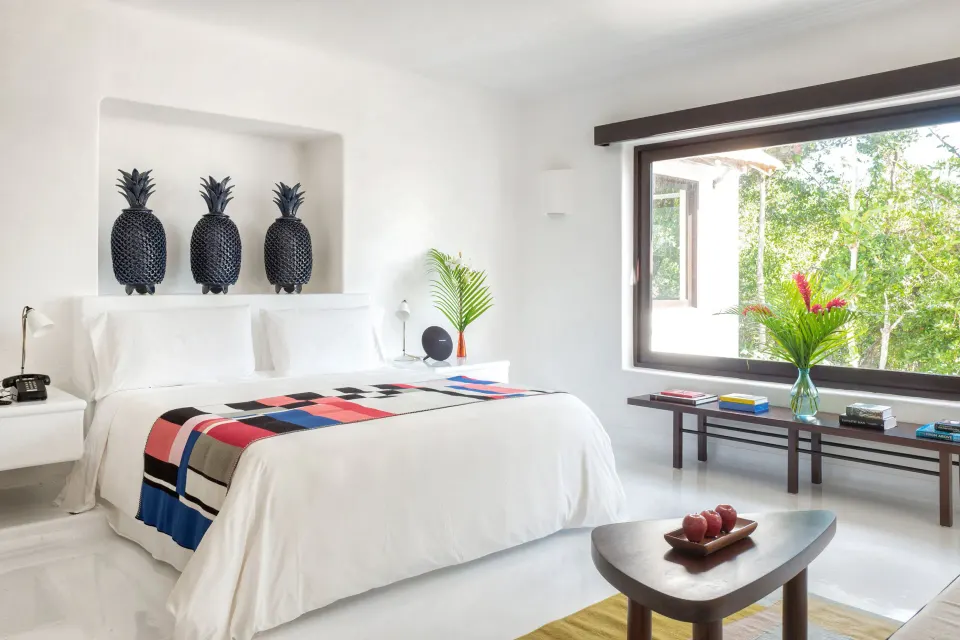 Bright white Esencia suite bedroom with king bed and window at Hotel Esencia