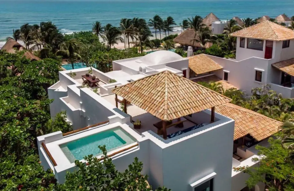 Aerial view of white villa roofs and private plunge pool near the beach at Hotel Esencia